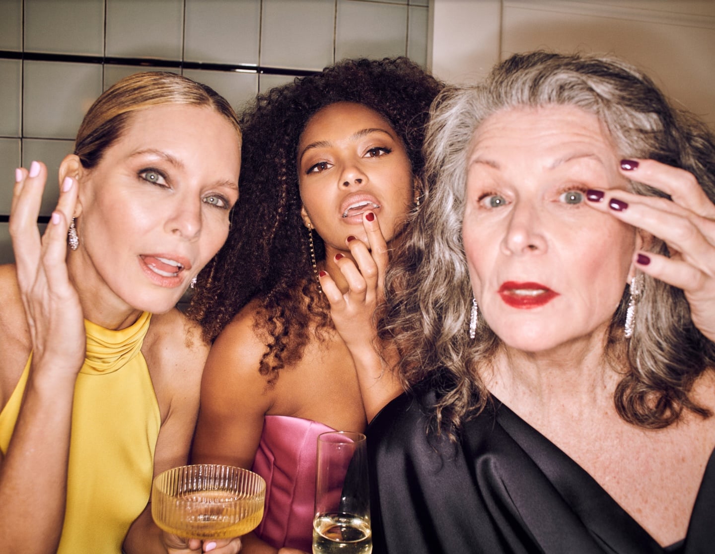 Friends with fresh hair and makeup posing with champagne at an at-home group glam session