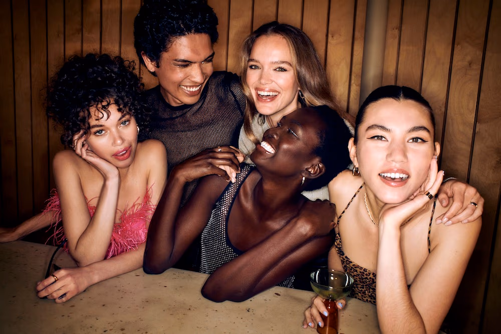 Group of friends with event-ready hair and makeup laughing together at a party